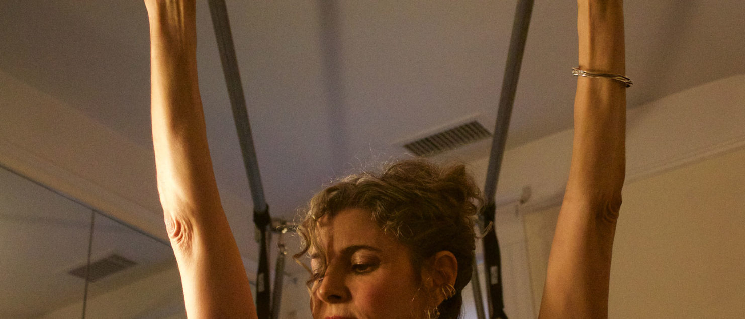 A woman is holding onto some bars in the air